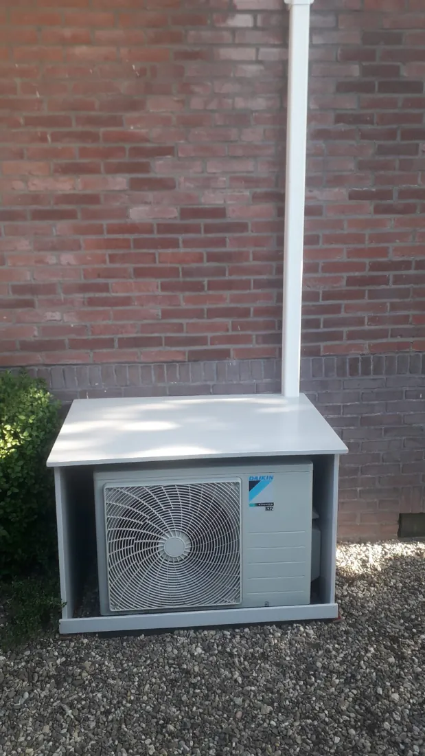 Daikin buitenunit netjes geplaatst op tegels tegen een bakstenen gevel